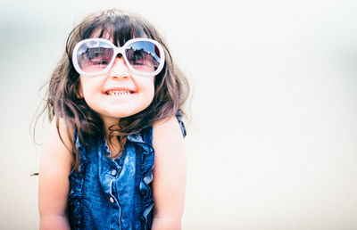 Portrait of smiling girl wearing sunglasses against white background
