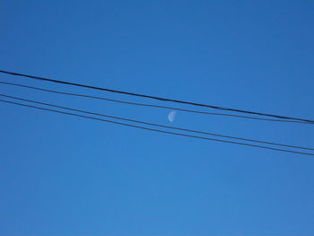 Low angle view of power lines against clear blue sky