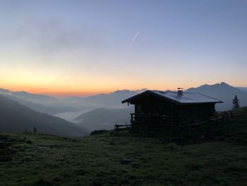 House on mountain against sky during sunset