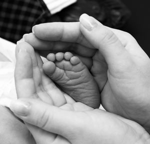 Cropped hand of woman holding baby feet