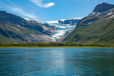 Scenic view of lake by snowcapped mountains against sky