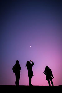 Silhouette people standing against clear sky at night