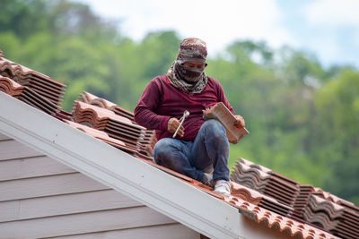 Low angle view of man sitting on roof