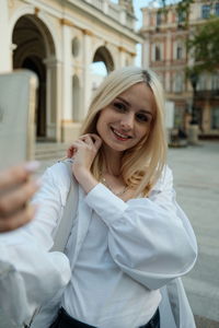 Beautiful young girl takes a selfie on a smartphone on the street. high quality photo