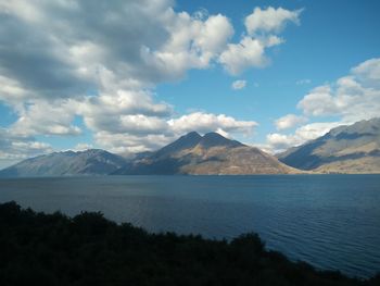 Scenic view of lake and mountains against cloudy sky