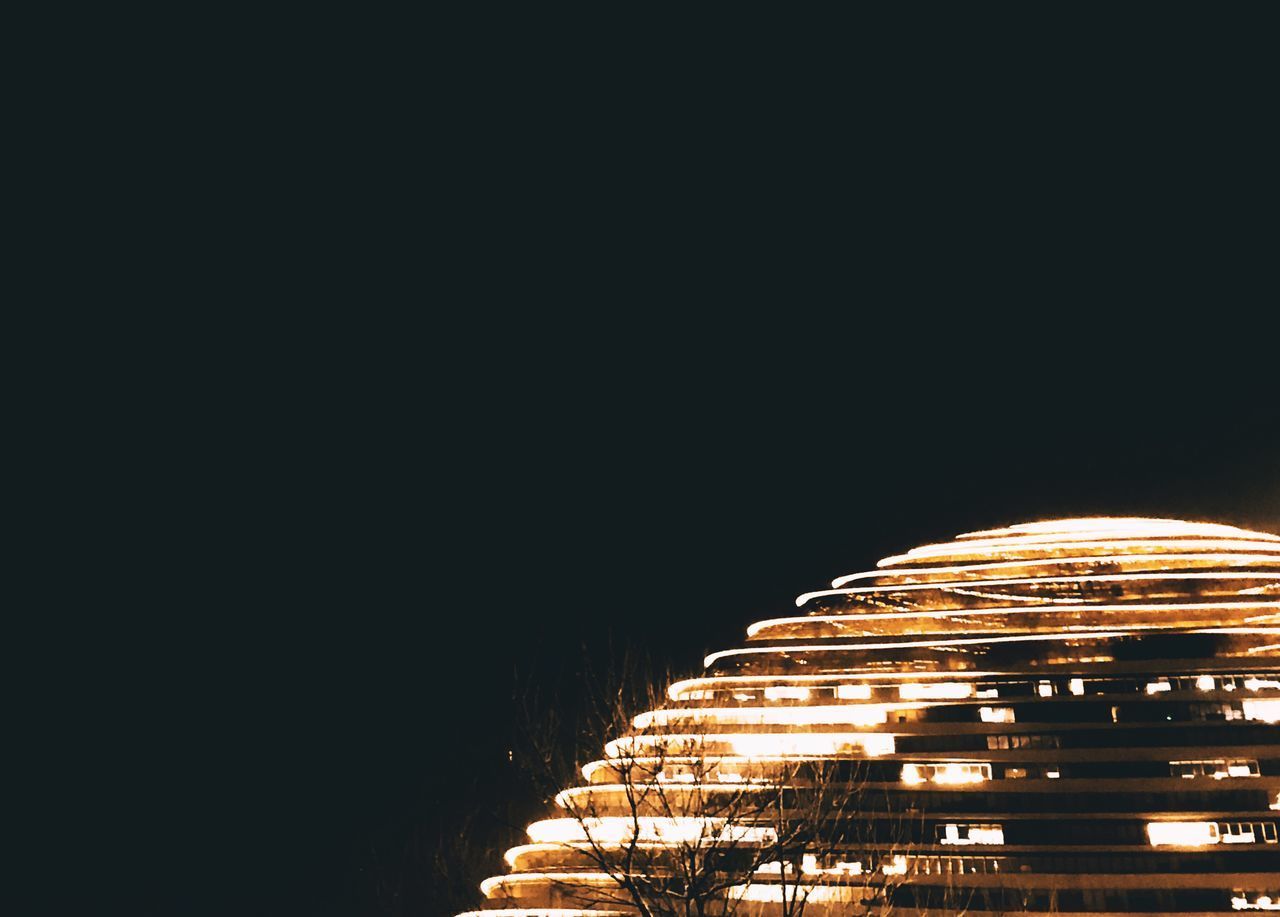 LOW ANGLE VIEW OF ILLUMINATED BUILDINGS AGAINST SKY AT NIGHT