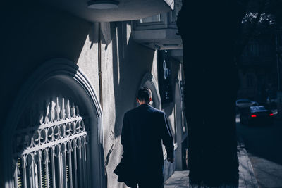 Rear view of man standing on street amidst buildings in city