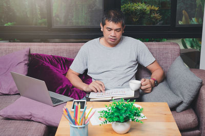 Portrait of man using digital tablet while sitting on sofa at home