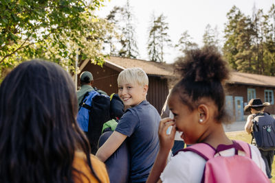 Portrait of smiling boy looking over shoulder while walking with friends at summer camp