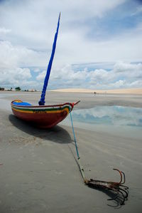 Boat moored at beach against sky