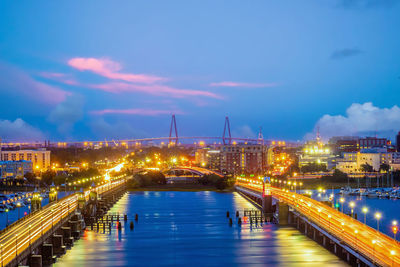 Illuminated bridge over river against sky at night