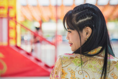 Beautiful asian woman wearing traditional yellow cheongsam qipao dress standing in a chinese temple