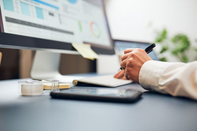 Woman working on computer and smartphone in office. closeup of female hand at desktop. office work