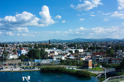 Aerial view of city by river against sky