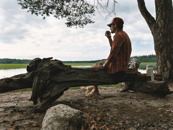 Rear view of man sitting on rock at beach