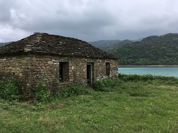 House on field by mountain against sky