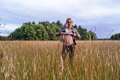 Portrait woman showing abdomen while standing on field