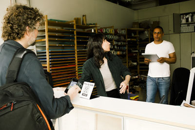 Customer collecting serviced laptop while standing at repair shop