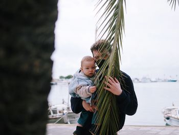 Rear view of mother with son standing in water