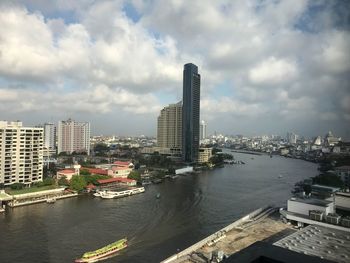 Buildings by river against sky in city