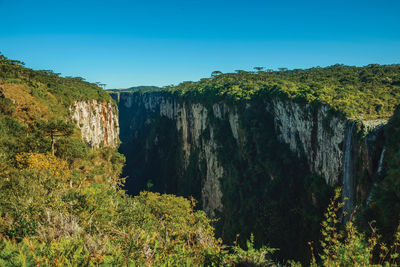 Itaimbezinho canyon and waterfall coming from rocky cliffs with forest, near cambará do sul, brazil.