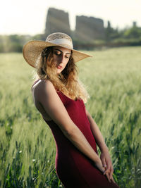 Portrait of young woman wearing hat standing on field