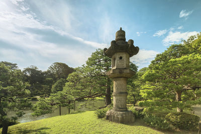 View of a japanese stone kasuga lantern against cloudy summer sky