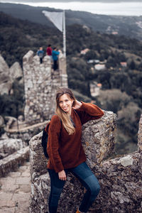 Portrait of young woman standing on stairs in tower against sky