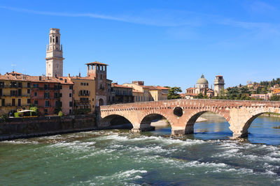 Arch bridge over river against buildings