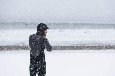 Man preparing to go surfing during winter snow