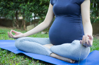 Low section of pregnant woman practicing yoga in park