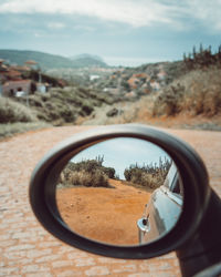 Reflection of dirt road on side-view mirror