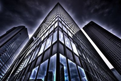 Low angle view of skyscrapers against cloudy sky