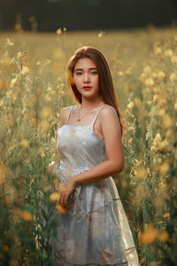 Portrait of beautiful young woman standing on field