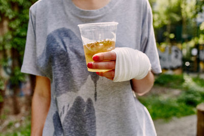 Midsection of woman with bandage on hand holding drink