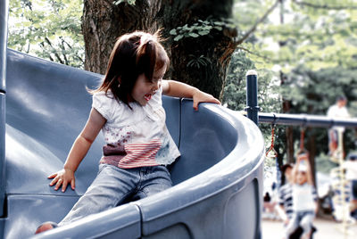 Playful girl enjoying slide at park