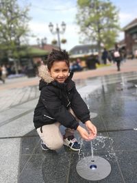 Portrait of boy crouching by fountain