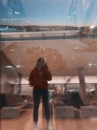 Reflection of man photographing on glass window