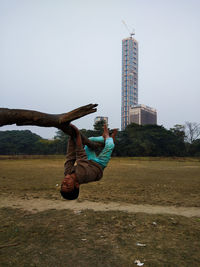 Man with arms raised on field against sky