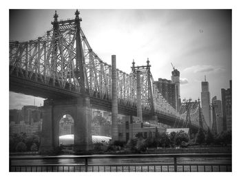 Low angle view of queensboro bridge over east river by city against sky