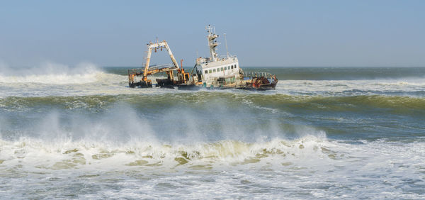 Wreck of fishing boat in rough atlantic ocean with high waves, coast of namibia, africa