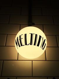 Low angle view of illuminated electric light against tiled wall