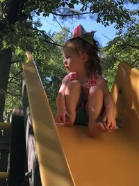 Full length of cute girl sitting on slide