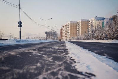 Road by snow covered city against sky