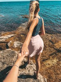 Cropped man holding hand of woman at beach