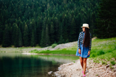 Woman standing by lake in forest