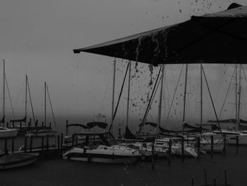 Sailboats moored at harbor against clear sky