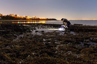 Women researching on rocky shore at night