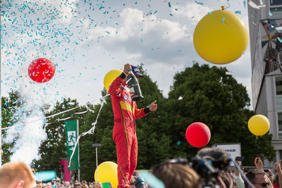 People with balloons against sky