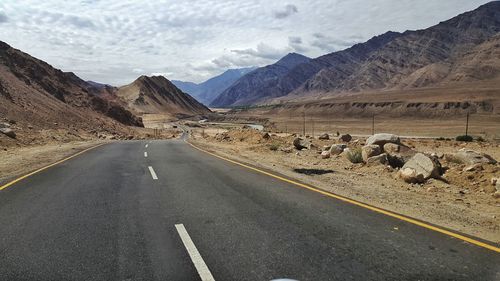 Road leading towards mountains against sky